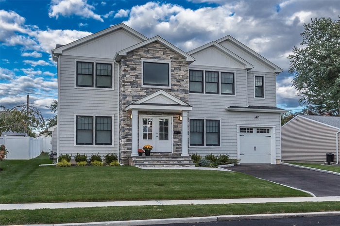 View of front of house with an attached garage, asphalt driveway, and board and batten siding