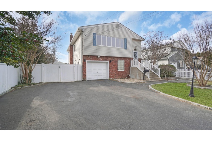 View of front of home with a gate, fence, an attached garage, aphalt driveway, and brick siding