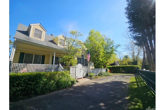 View of side of property with fence, a porch, and asphalt driveway