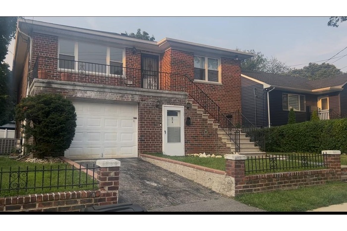 View of front of property with brick siding, asphalt driveway, and an attached garage