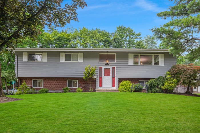 Bi-level home with a front lawn and brick siding