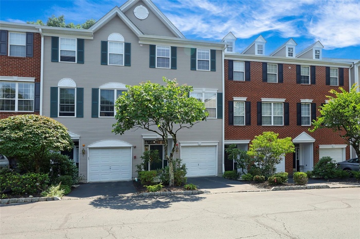 Colonial-style house featuring driveway, an attached garage, and brick siding