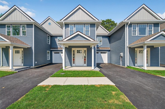 View of front of property featuring board and batten siding, a garage, asphalt driveway, and covered porch