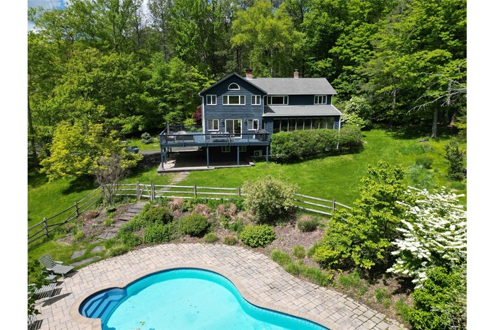 Back of property featuring a chimney, a deck, and a wooded view