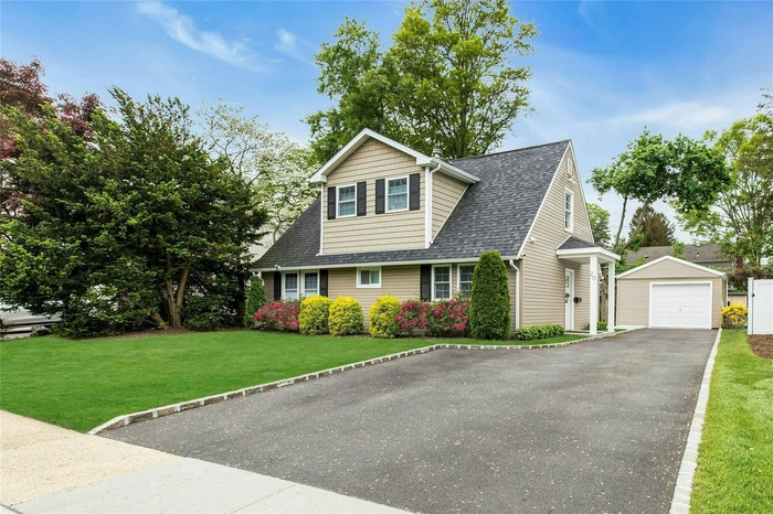View of front of property with  a garage, a shingled roof, a front yard, and driveway, beautiful Rose bushes.