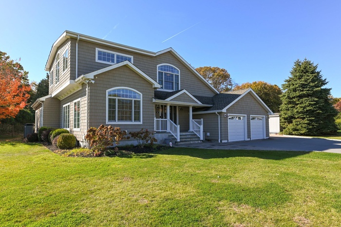 View of front facade with a front yard, a garage, and driveway
