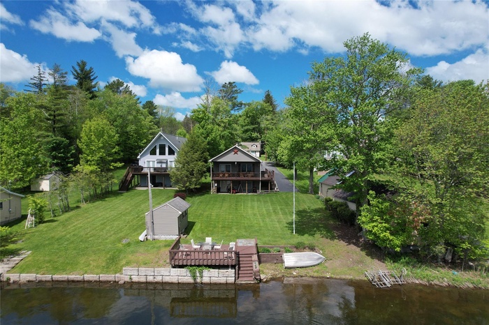 Rear view of house featuring a deck with water view, a yard, stairway, and an outdoor structure