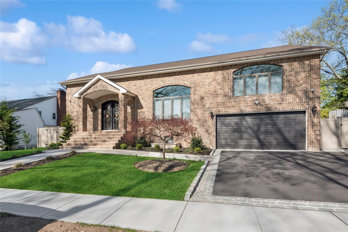View of front of home featuring a front lawn, brick siding, driveway, and a garage