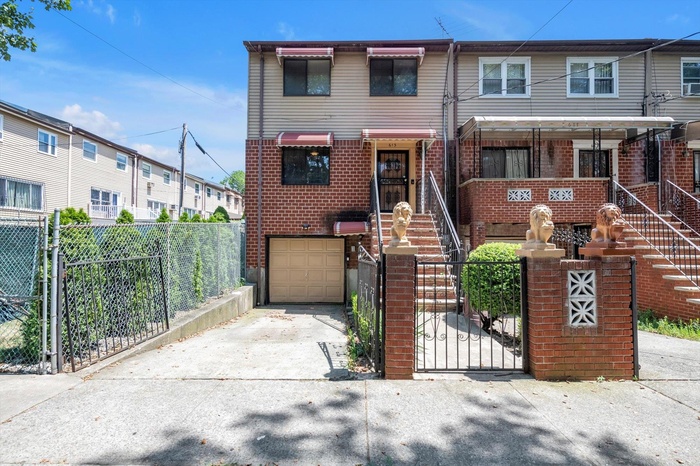 Traditional home featuring a garage, concrete driveway, a fenced front yard, and brick siding