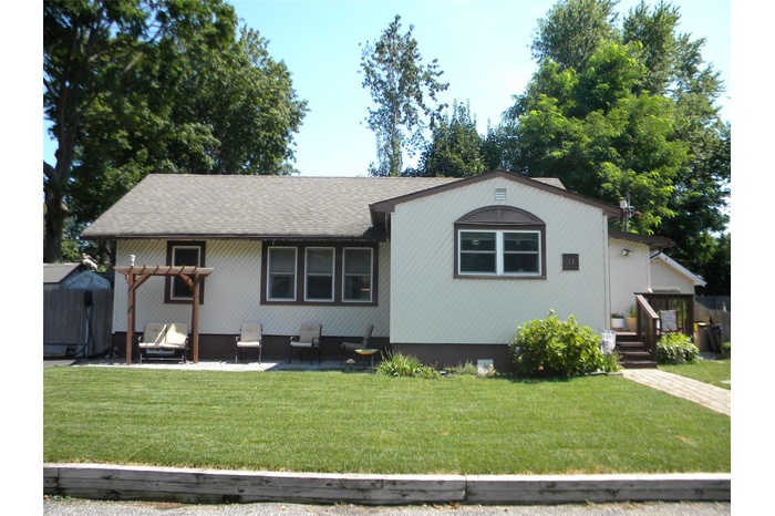 View of front facade featuring a front yard, a patio area, and a shingled roof