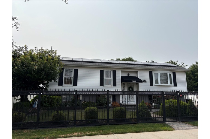 View of front of property featuring solar panels and a fenced front yard