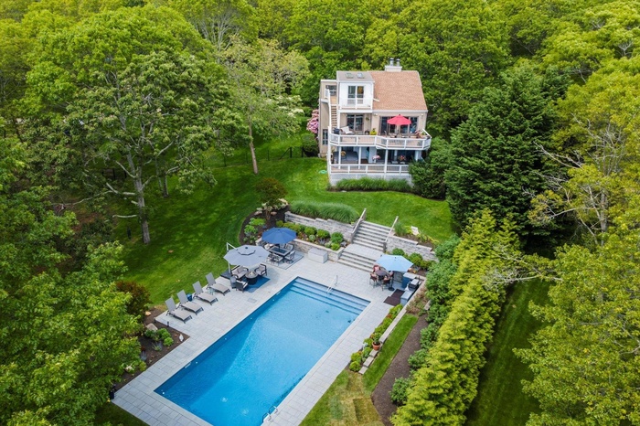 View of subject property featuring a forest and a pool