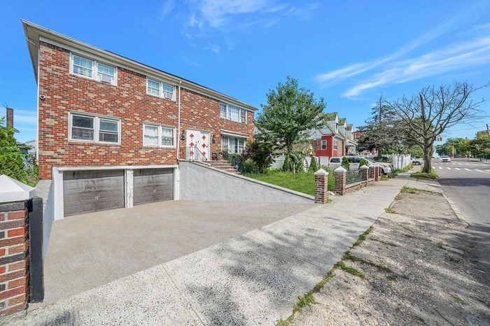 View of front of property with an attached garage, concrete driveway, brick siding, and a residential view