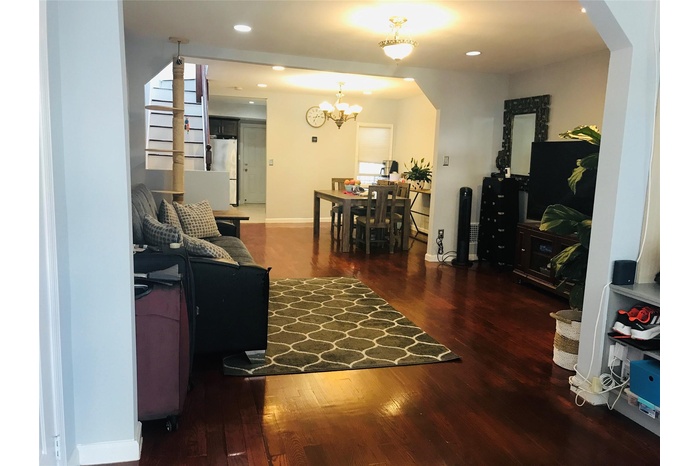 Living area with arched walkways, wood finished floors, a chandelier, and recessed lighting