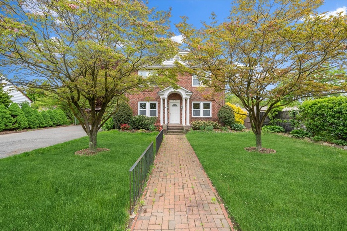 View of front facade featuring a front yard and brick siding