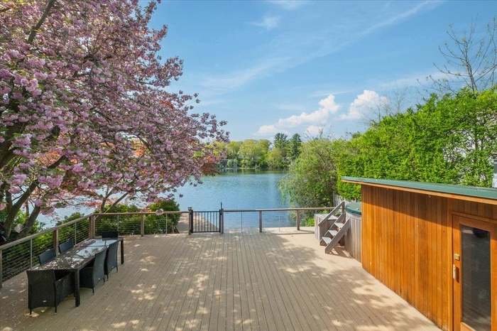 Wooden deck featuring a water view, sauna and hot tub