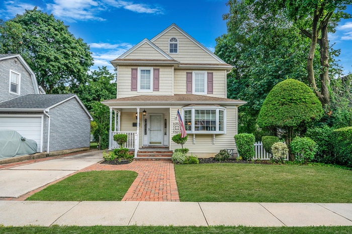 View of front of house with covered porch and a front yard
