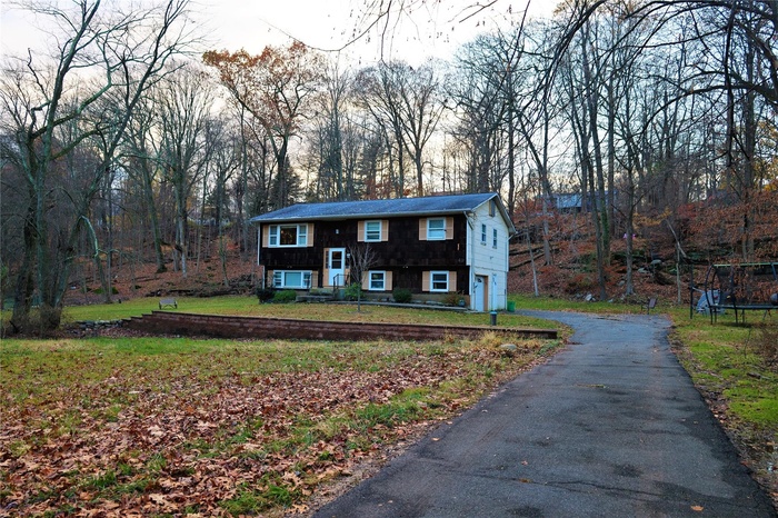 Split foyer home with a trampoline, an attached garage, asphalt driveway, and a front lawn