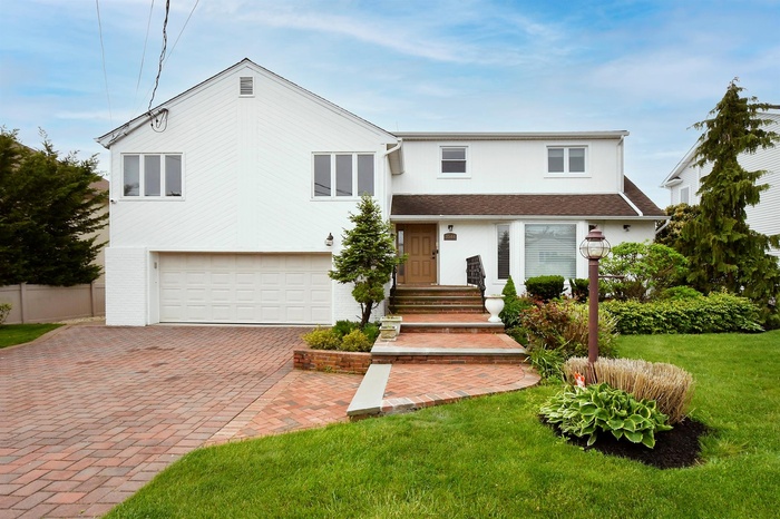 View of front of house featuring an attached garage, decorative driveway, and roof with shingles