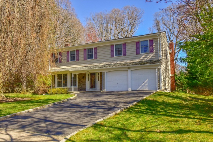Traditional-style home with a chimney, an attached garage, driveway, and a front yard
