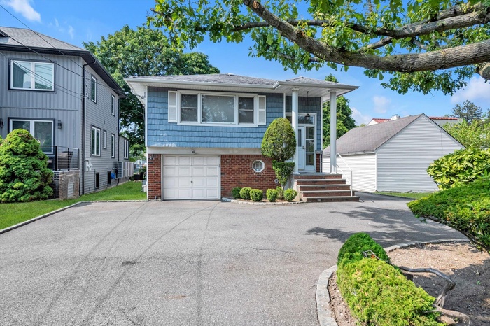 View of front of property with brick siding, asphalt driveway, and an attached garage