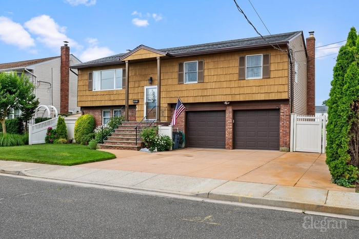 Split foyer home with brick siding, concrete driveway, a garage, and a shingled roof