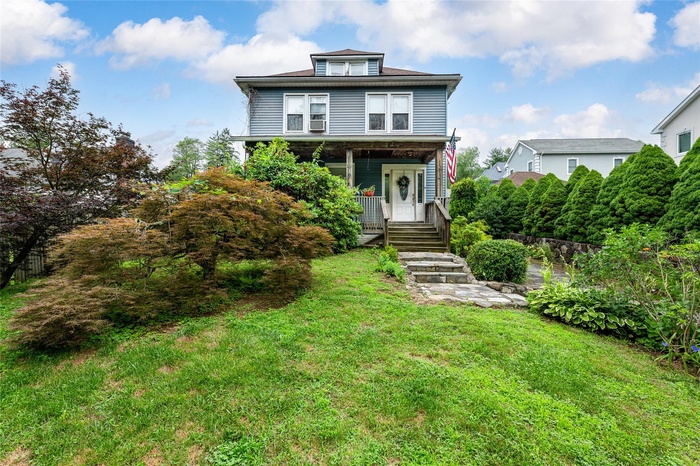 Front of home with covered porch and a front yard