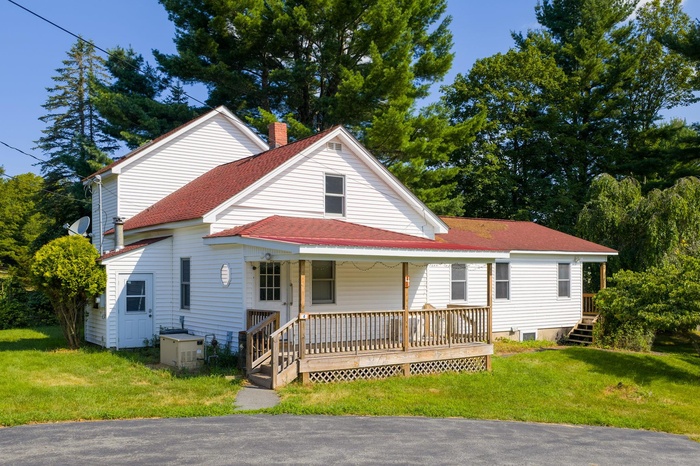 View of side of property with a shingled roof, a porch, a back lawn view