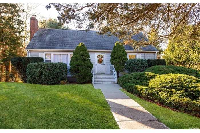 New england style home with a shingled roof, a chimney, and a front yard