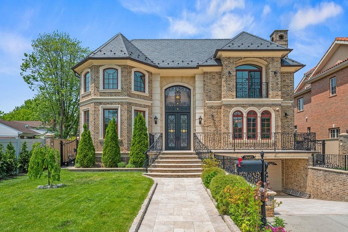 View of front of property featuring french doors, a high end roof, brick siding, and a front yard