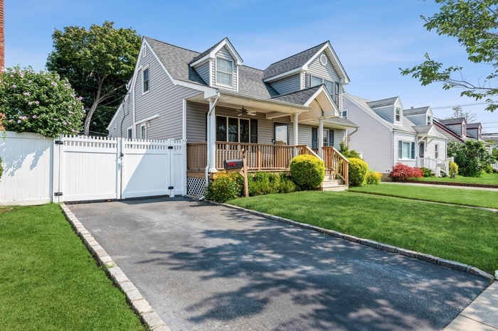 Cape cod home featuring a gate, a porch, roof with shingles, and a ceiling fan