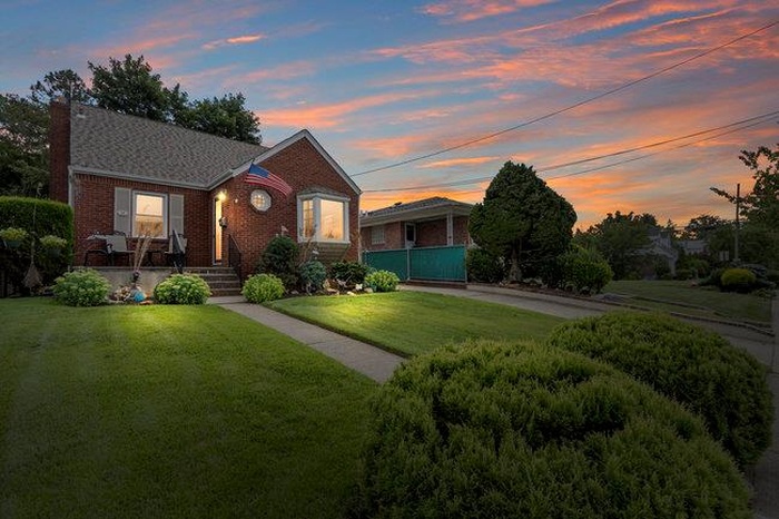 View of front of property with brick siding, a yard, and a chimney
