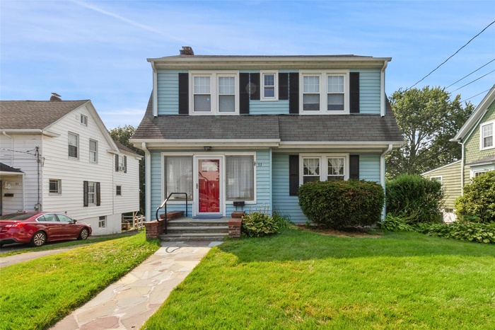 View of front of home featuring a front lawn, a chimney, and a shingled roof