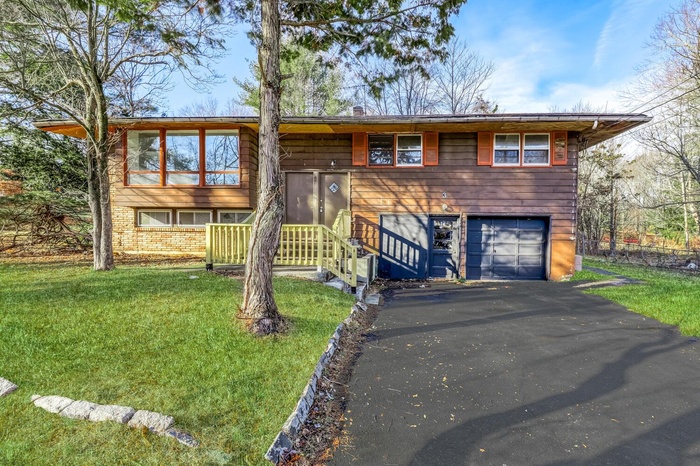 Split foyer home with driveway, a front lawn, and a garage