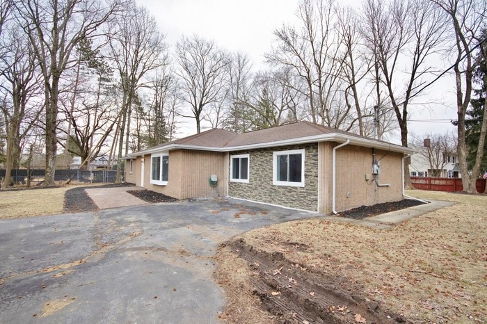 View of front of house featuring driveway and stone siding