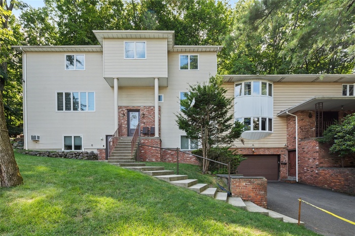View of front of property with a garage, brick siding, asphalt driveway, and a front lawn