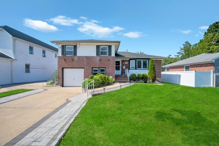 Split level home featuring brick siding, concrete driveway, and a garage