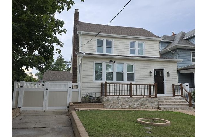 View of front of property featuring a gate, a chimney, and a shingled roof