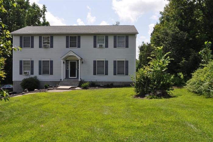 Colonial-style house featuring a front yard