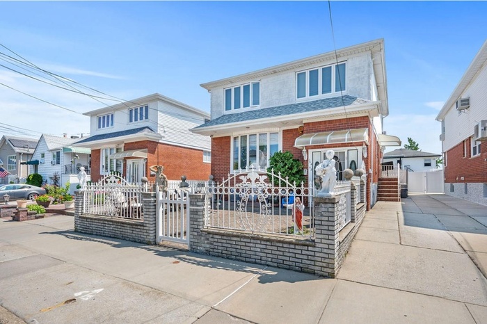 View of front of house featuring a gate, a fenced front yard, brick siding, and roof with shingles