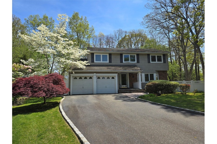 Traditional-style home featuring an attached garage, fence, aphalt driveway, a front yard, and roof with shingles