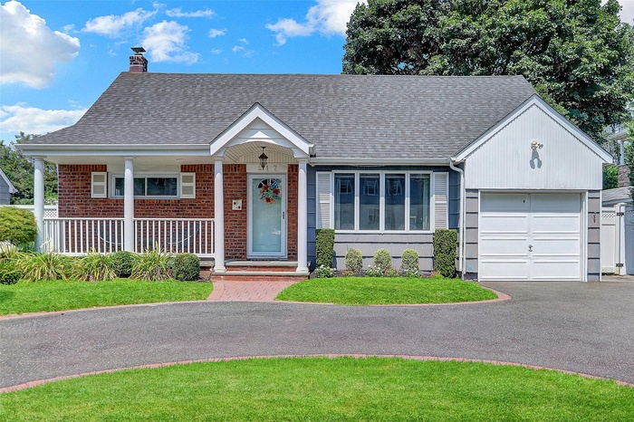Ranch-style home featuring a shingled roof, a chimney, brick siding, a garage, and covered porch