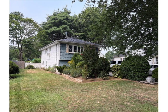 View of front facade featuring a vegetable garden and view of wooded area