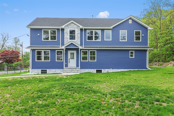 View of front of property featuring fence, entry steps, and a front lawn