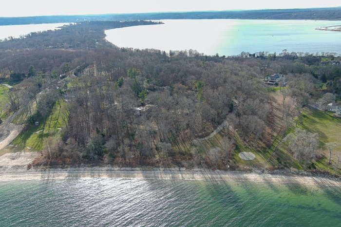 Aerial view of property's location featuring a nearby body of water and a heavily wooded area