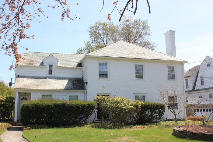 View of side of home featuring a high end roof, a lawn, and a chimney