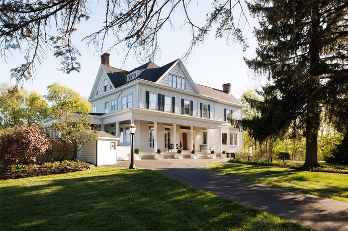 View of front facade with a porch, a chimney, and a front yard