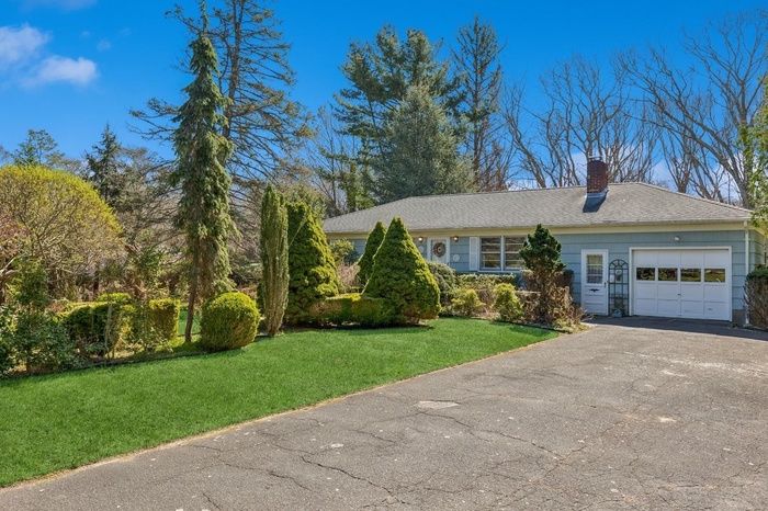 View of front of property with a garage, a front yard, aphalt driveway, and a chimney
