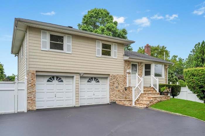 Tri-level home with a garage, asphalt driveway, and a chimney