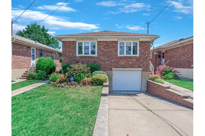 View of front facade with driveway, a garage, a front yard, brick siding, and stairs